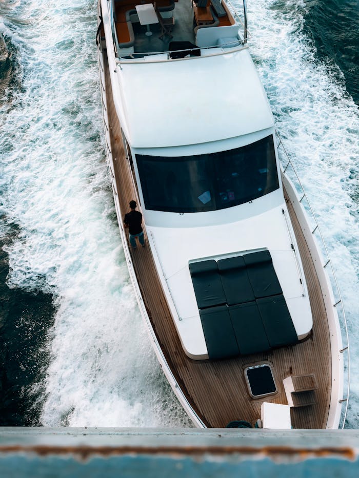 Dynamic aerial view of a luxury yacht making its way through vibrant blue ocean waters.